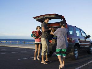 Family unloading back of vehicle at beach